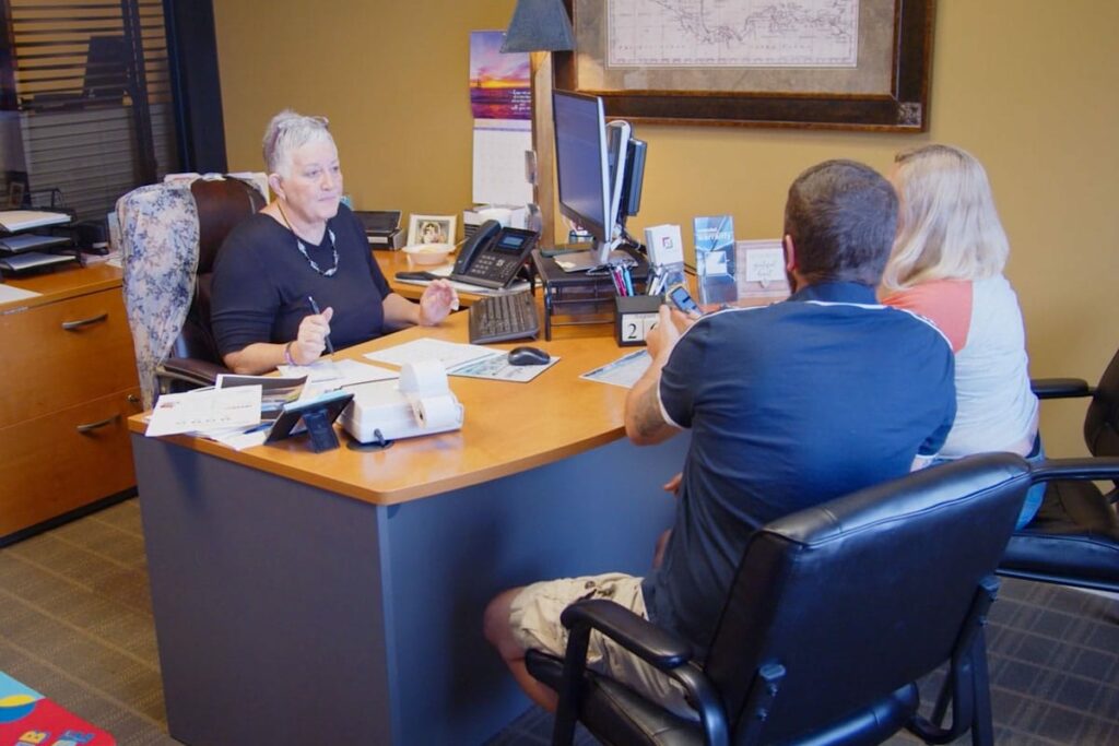 Colonial Loan agent sitting at desk across from clients